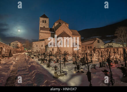 Cimetière de nuit, tout près de la croix, l'église en arrière-plan, il devient matin, neige au sol, des tombes couvertes de neige Banque D'Images