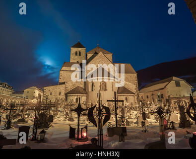 Cimetière de nuit, tout près de la croix, l'église en arrière-plan, il devient matin, neige au sol, des tombes couvertes de neige Banque D'Images