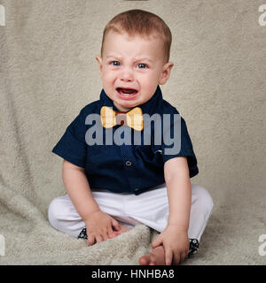 Baby Boy crying while looking at camera sitting on blanket Banque D'Images