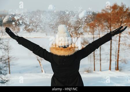 Girl Throwing Snow dans l'air pendant l'hiver Banque D'Images