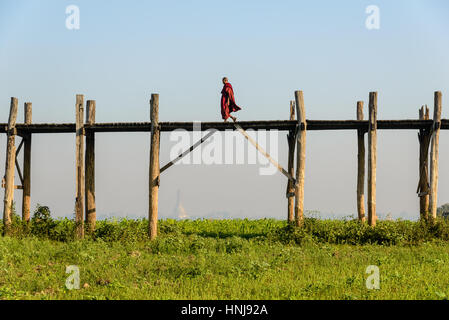 AMARAPURA, MYANMAR - février 20, 2014 : moine marchait sur le pont U Bein, le plus long pont en teck du monde Banque D'Images