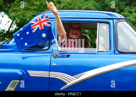 L'homme forme à partir d'une voiture vintage bleu avec un drapeau australien participe à la Journée de l'Australie 2017 parade, Berrima, New South Wales, Australie Banque D'Images