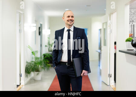 Swedish caucasian man en costume et cravate. L'origine ethnique européenne scandinave. Les bureaux de l'intérieur. Sourire et de transporter l'ordinateur portable. Banque D'Images