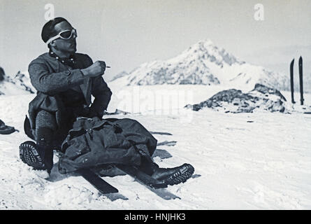 Col de Sorel, Italie 1939 - jeune skieur tannées portant des lunettes de soleil assis sur le dessus, le repos avec une cigarette à la main. Numérisation à partir de la photographie analogique, la collection de la famille privée avant la DEUXIÈME GUERRE MONDIALE. Banque D'Images