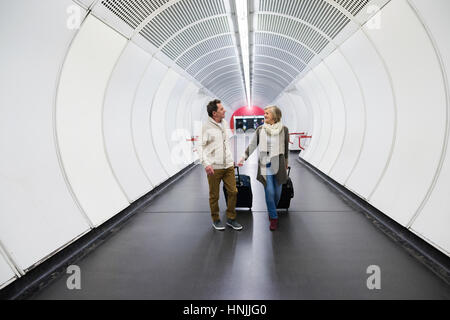 Couple dans le couloir du métro tirant poussette. Banque D'Images