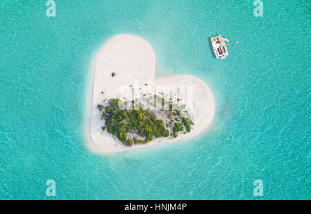 Belle petite île tropicale en forme de cœur, ancrage bateau catamaran. Banque D'Images