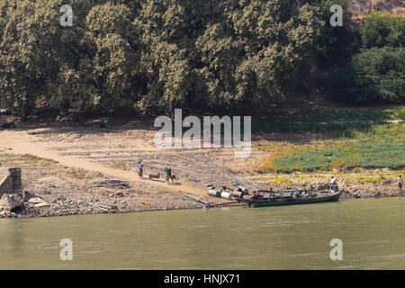 Quatre hommes transportant une lourde 45 gallons baril dans une écharpe de la rive d'un cargo sur le fleuve Irrawaddy à Mandalay (Birmanie). Banque D'Images