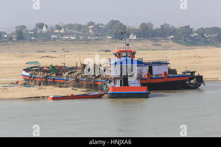 Une grande barge de gravier est déchargé sur les rives de l'Irrawaddy au Myanmar (Birmanie). La récupération d'or écluses semblent être en activité aussi. Banque D'Images