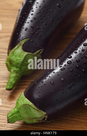 Photo de deux aubergines avec les gouttelettes d'eau sur une table en bois. Banque D'Images