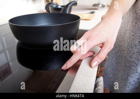 La femme moderne comprend une cuisinière à induction Banque D'Images