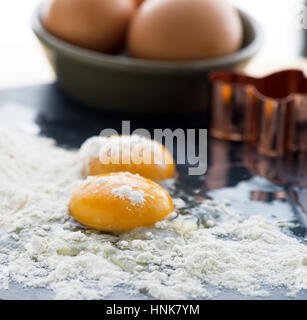 Les œufs crus l'accent sur l'œuf avec la farine et les oeufs entiers en arrière-plan, selective focus à ad copie espace tourné en un carré, formatt Banque D'Images