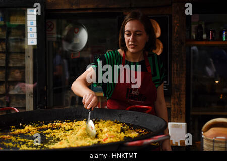 Chef de cuisine et de vendeur de rue en remuant paella dans Camden Lock Market, Londres, Royaume-Uni. Banque D'Images