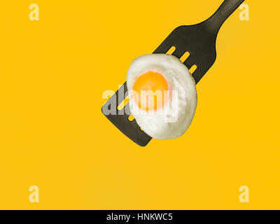 Oeuf au plat sur une spatule 3/4-vue aérienne sur fond jaune Banque D'Images