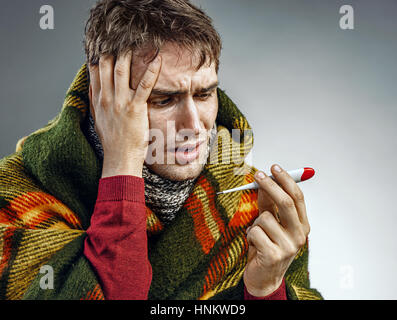 Homme choqué de lire sa température au thermomètre. Photo de malade souffrant d'hiver froid et le virus de la grippe aviaire. Banque D'Images