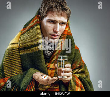 Homme malade avec visage fatigué expression, prise de médicaments comprimés. Photo d'un homme souffrant rhume et grippe d'hiver. Banque D'Images