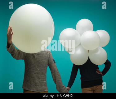 Couple heureux avec des ballons au lieu d'une tête sur un fond bleu Banque D'Images