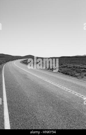 Les collectivités éloignées, rurales route tournant autour d'un coin dans la distance. Banque D'Images