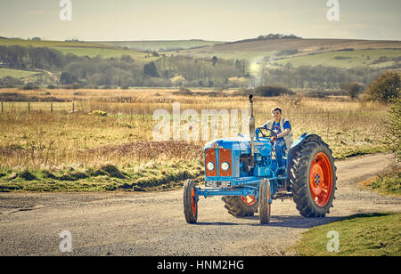 Bleu et rouge Vintage tracteur roulant dans la campagne Banque D'Images