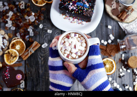 Tasse de chocolat chaud dans les mains sur un arrière-plan de la table avec des bonbons et des gâteaux, vue d'en haut Banque D'Images