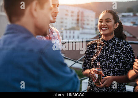 Jeune femme debout sur la bière avec des amis sur le toit. Les personnes ayant du bon temps à partie. Banque D'Images