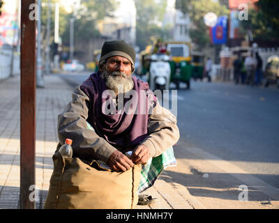 Ahmadabad, Gujarat, Inde - Le 30 janvier : les pauvres paysans indiens est en attente de l'autobus s'accroupissant par le sac avec le riz dans la ville d'Ahmedabad Banque D'Images