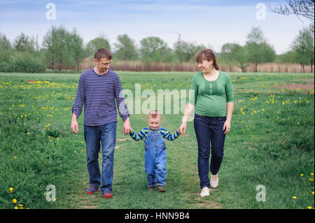 Jeune famille et jeune fils marche sur une prairie de printemps Banque D'Images