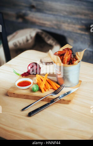 Harnished ailes de poulet avec la sauce et des légumes sur la table en bois Banque D'Images