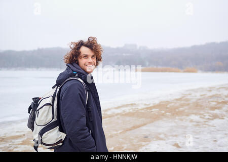 Jeune homme souriant avec un sac à dos sur la nature de l'hiver printemps Banque D'Images