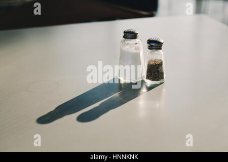 Sunlit Sel & poivre sur une table d'une grande ombre Banque D'Images