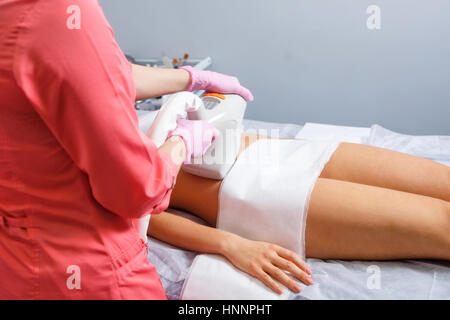 Massage sous vide de l'abdomen d'une jeune fille. Cosmétologie matérielles. Studio Spa. L'homme est méconnaissable. Banque D'Images