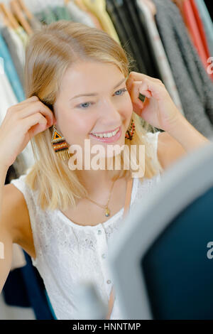 Dame holding paire de boucles d'oreilles à dangly Banque D'Images