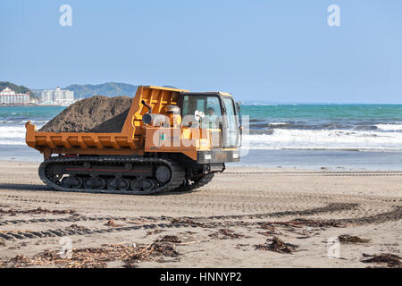 KAMAKURA, JAPON - CIRCA avr 2013 : Crawler transporter plein de sable sur une plage de sable sur la côte de l'océan Pacifique. Travaux d'amélioration de la plage municipale Banque D'Images