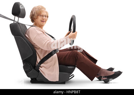 Femme âgée assise dans un siège de voiture tenant un volant et regardant la caméra isolé sur fond blanc Banque D'Images