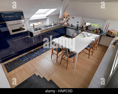 Ntérieur d'une cuisine moderne avec table à manger dans le grenier romm dont le sol est en bois Banque D'Images