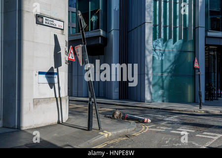 Un homme d'affaires donne sur le coin de rue où un bollard endommagé se trouve à l'horizontal, renversé par un véhicule le 13 février 2017, dans la ville de Londres, Royaume-Uni. Banque D'Images