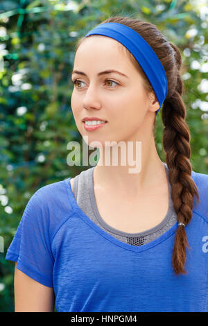 Portrait of smiling sporty brunette woman in blue sportswear outdoor. Mettre en place, sportif et athlétique jeune femme. Belle fille dans un sport. Hairstyle Banque D'Images