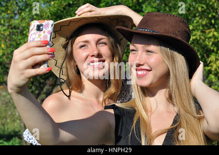 Deux adolescentes à chapeaux de cow-boy en tenant à l'été jour selfies Banque D'Images