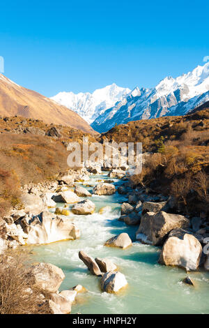 Vue paysage de rivière qui traverse la vallée de Langtang avec vue sur les sommets de montagnes de l'Himalaya et l'arrière-plan Gangchenpo Peak au Népal Banque D'Images