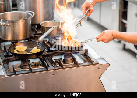 La friture steak viande Chef sur la cuisinière à gaz avec le feu à la cuisine. Vue rapprochée sur la poêle Banque D'Images