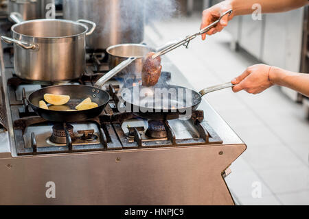 La friture steak viande Chef sur la cuisinière à gaz à la cuisine. Vue rapprochée sur la poêle Banque D'Images