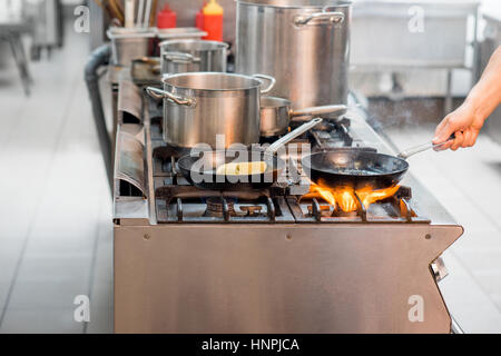 La friture steak viande Chef sur la cuisinière à gaz avec le feu à la cuisine. Vue rapprochée sur la poêle Banque D'Images