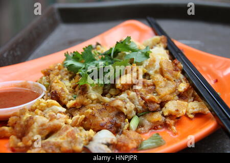 Omelette d'huîtres ou Orh Luak. Marché de nuit populaire / hawker food à Singapour. Garnir de feuilles de coriandre et servi avec la sauce chili. Banque D'Images