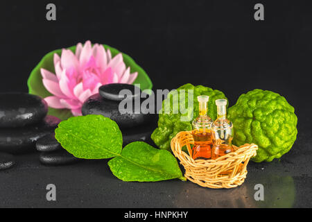 Spa concept de bergamote, Feuille, huile de parfum, lotus et des pierres de basalte zen avec de l'eau de la rosée sur fond noir, Close up Banque D'Images