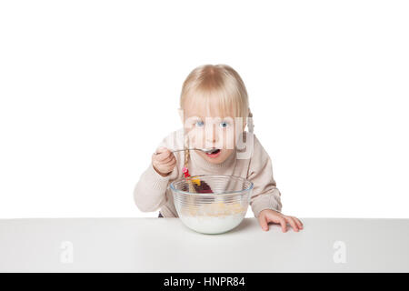 Smiling little girl eating flocons. Isolé sur fond blanc Banque D'Images