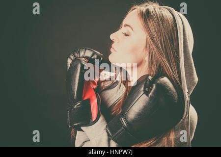 L'exercice de se préparer à se battre. L'esprit sportif et le corps solide. Regarder côté jeune femme porter des vêtements et des gants de boxe. Stand avec des mains croisées ho Banque D'Images