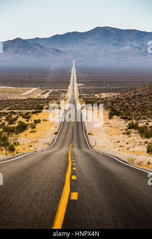 Classic vue verticale d'une route droite qui traverse les paysages arides de la célèbre vallée de la mort lors d'une journée ensoleillée en été, California, USA Banque D'Images