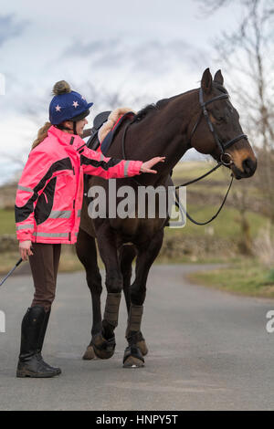 Adolescente cheval pur-sang de montage on rural road, North Yorkshire, UK. Banque D'Images