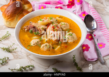 Soupe de boulettes de viande de poulet et les herbes dans un bol blanc avec cuillère et du pain Banque D'Images