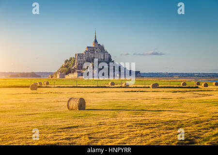 Belle vue sur le Mont Saint-Michel historique célèbre golden dans la lumière du soir au coucher du soleil en été avec des bottes de foin dans les champs, la Normandie, le nord de la France Banque D'Images