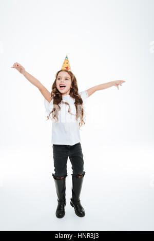 Smiling little girl in anniversaire hat célébrant et crier sur fond blanc Banque D'Images